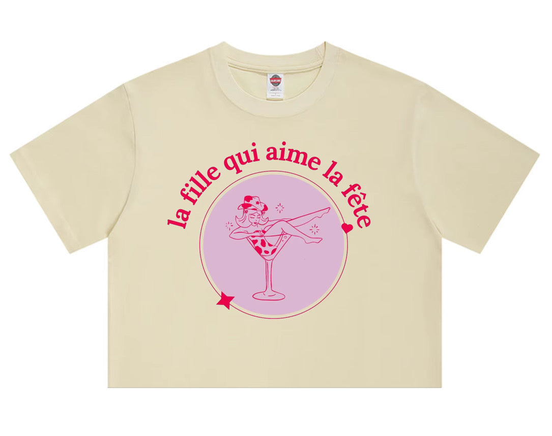 Cream t-shirt with pink “La Fille Qui Aime La Fête” French party girl graphic.