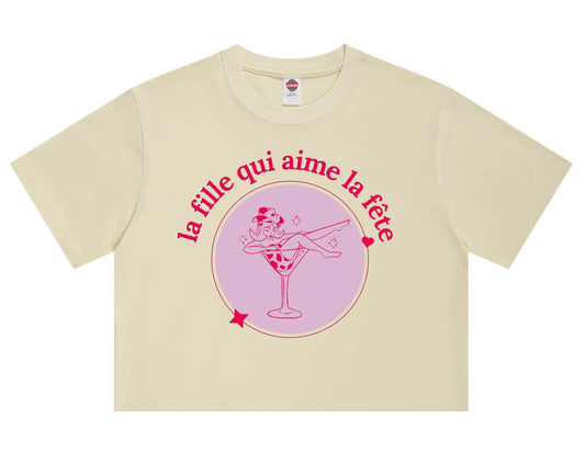 Cream t-shirt with pink “La Fille Qui Aime La Fête” French party girl graphic.