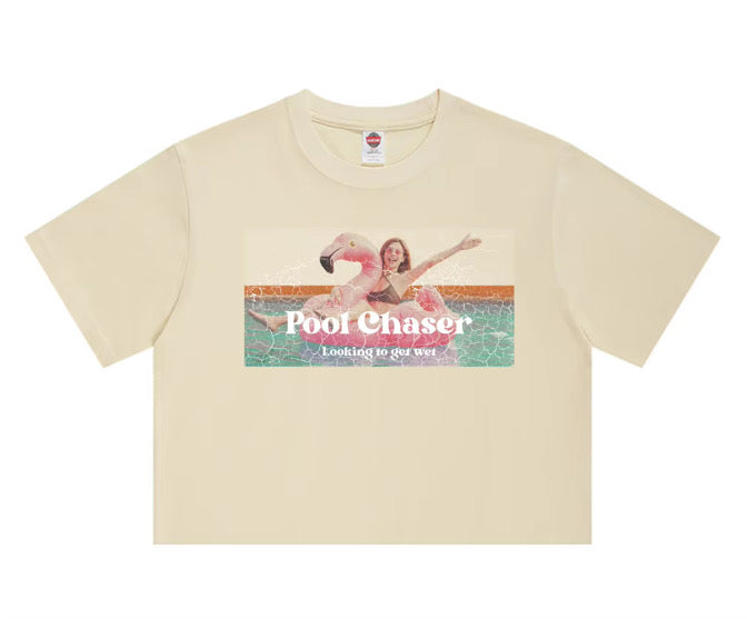 Cream t-shirt with a “Pool Chaser: Looking to Get Wet” graphic featuring a woman on a pink flamingo pool float.